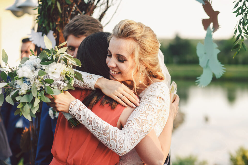 Bride in wedding dress hugging wedding officiant at the altar